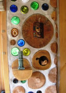 A cubby hole provides a little cave for a carved wooden dragon; a log-end shelf supports an artifact; a large red pine log-end next to a geode.